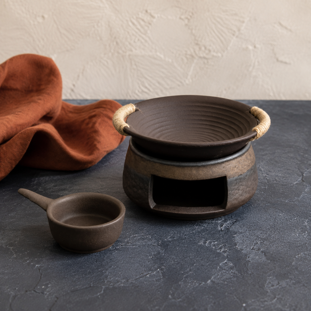 Rustic ceramic tea and aroma warmer three-piece set on a charcoal background.