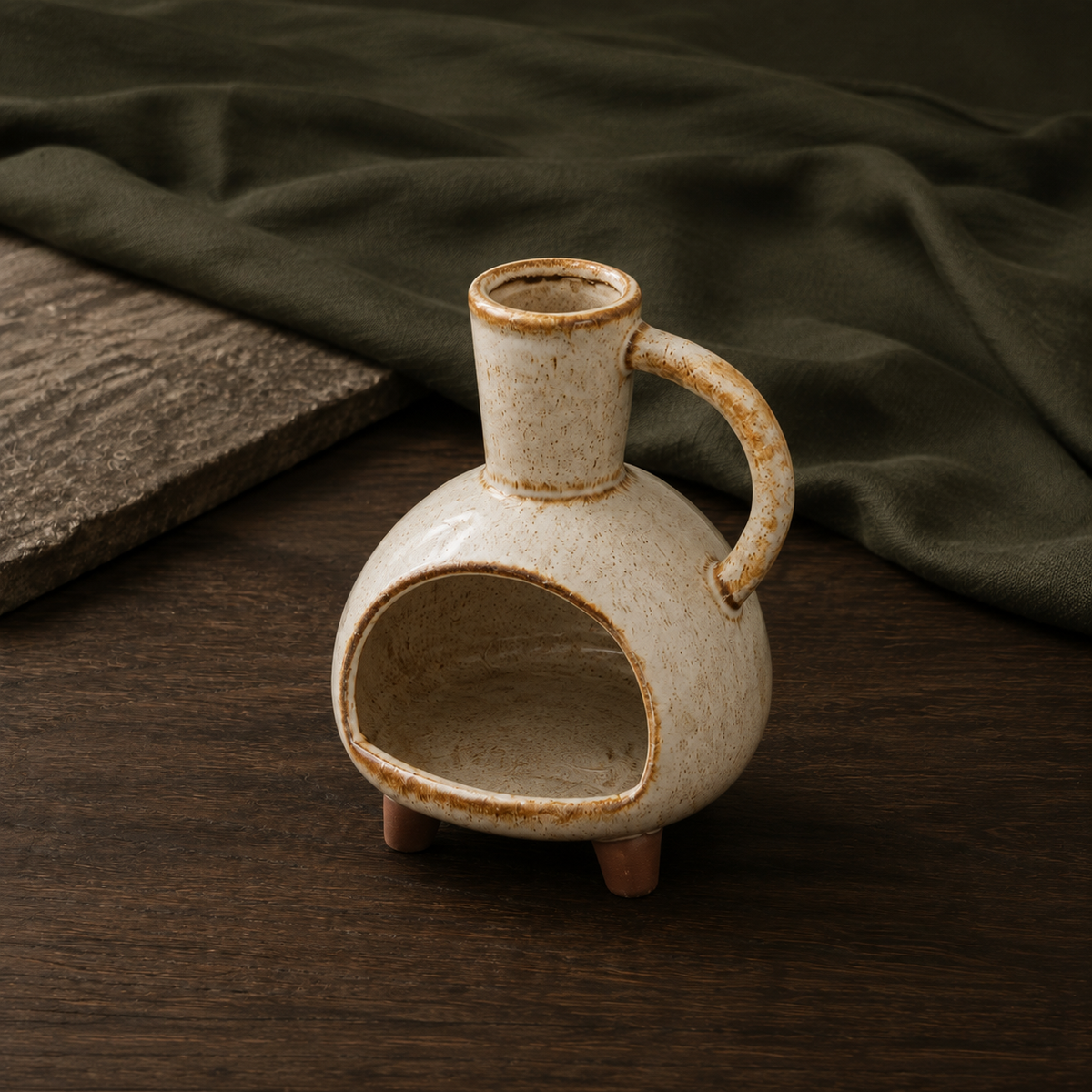Round Loop ceramic incense burner displayed on dark walnut with deep olive linen.