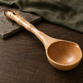Bamboo-node wooden ladle styled on warm paper and dark wood.