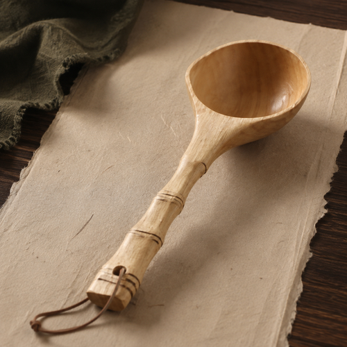 Full view of the wooden ladle with bamboo-inspired handle and hanging loop.
